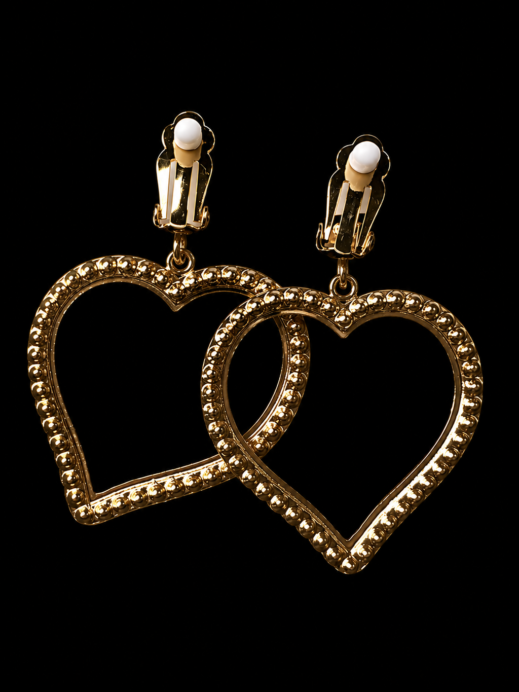 Gold heart-shaped earrings on a black background