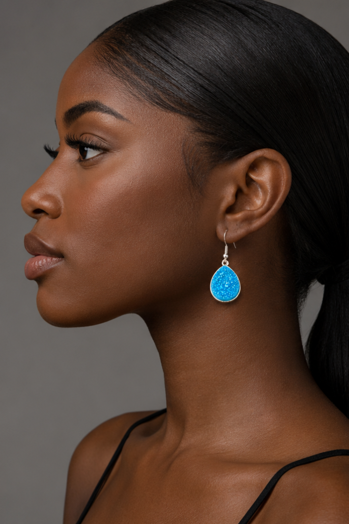 Woman wearing a blue earring against a neutral background