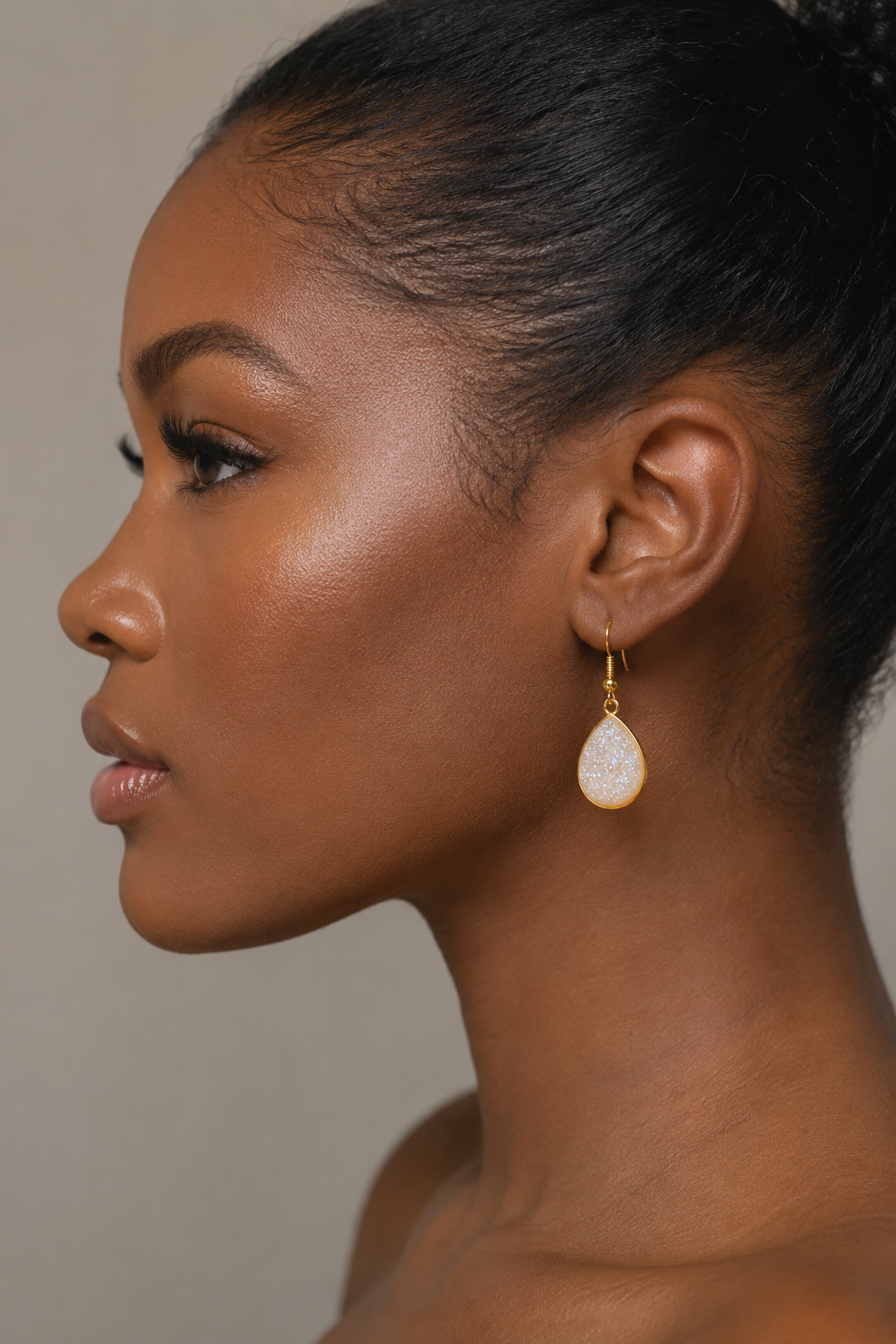 Close-up of a woman's profile wearing a gold earring against a neutral background