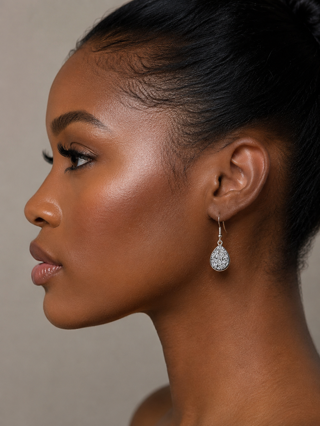 Side profile of a woman wearing a diamond earring against a neutral background