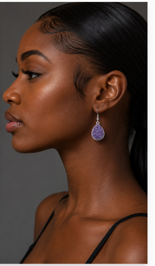 Woman wearing a purple teardrop earring against a neutral background
