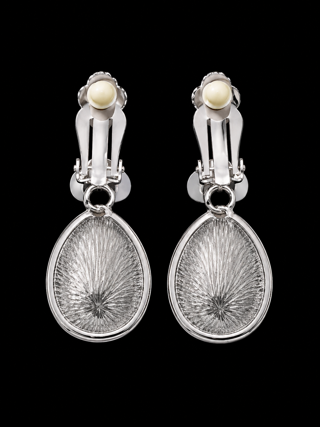 Pair of silver earrings with textured design and pearl-like stones on a black background