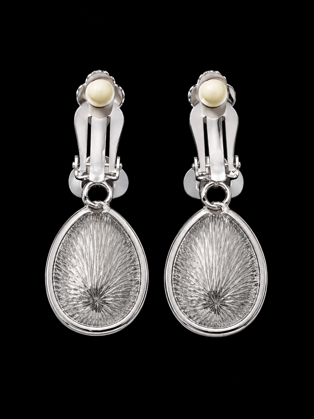 Pair of silver earrings with textured design and pearl-like stones on a black background