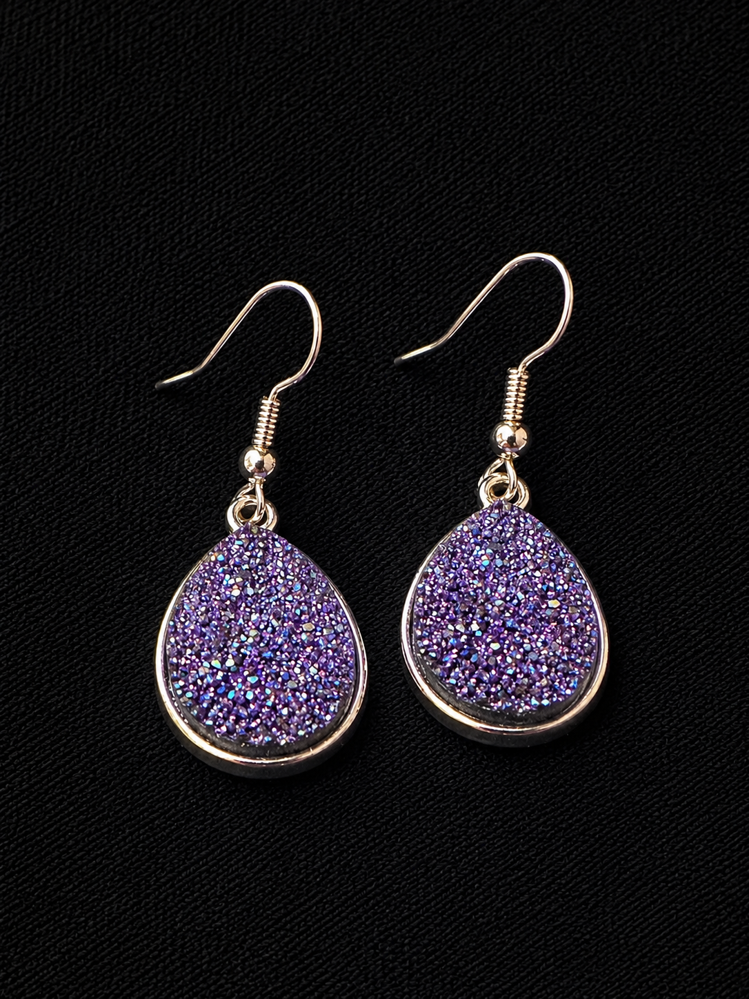 Purple druzy teardrop earrings on a black background