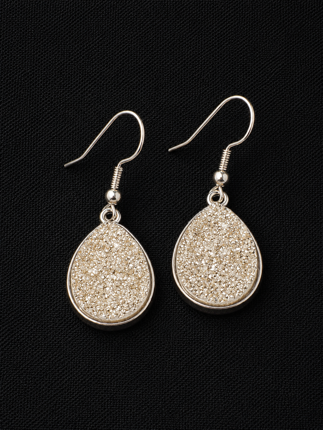 Silver teardrop earrings on a black background