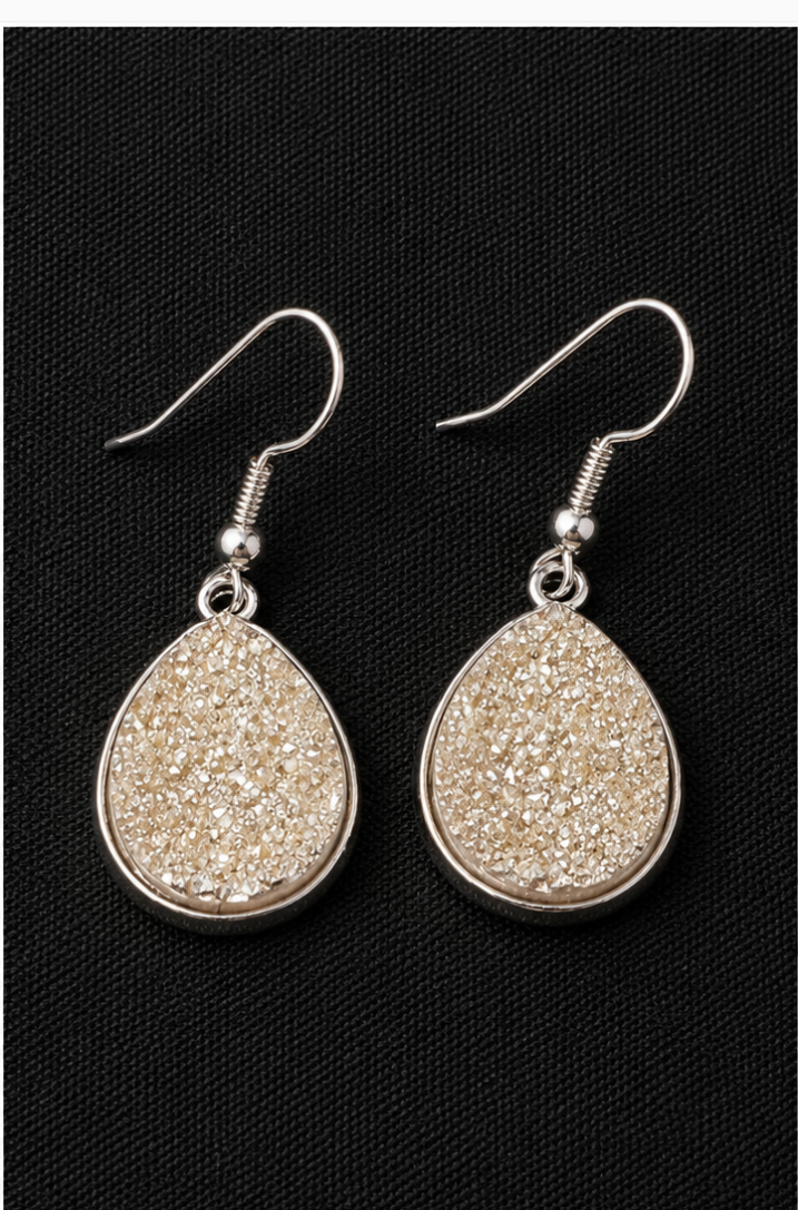 Teardrop-shaped earrings with glittery finish on a black background